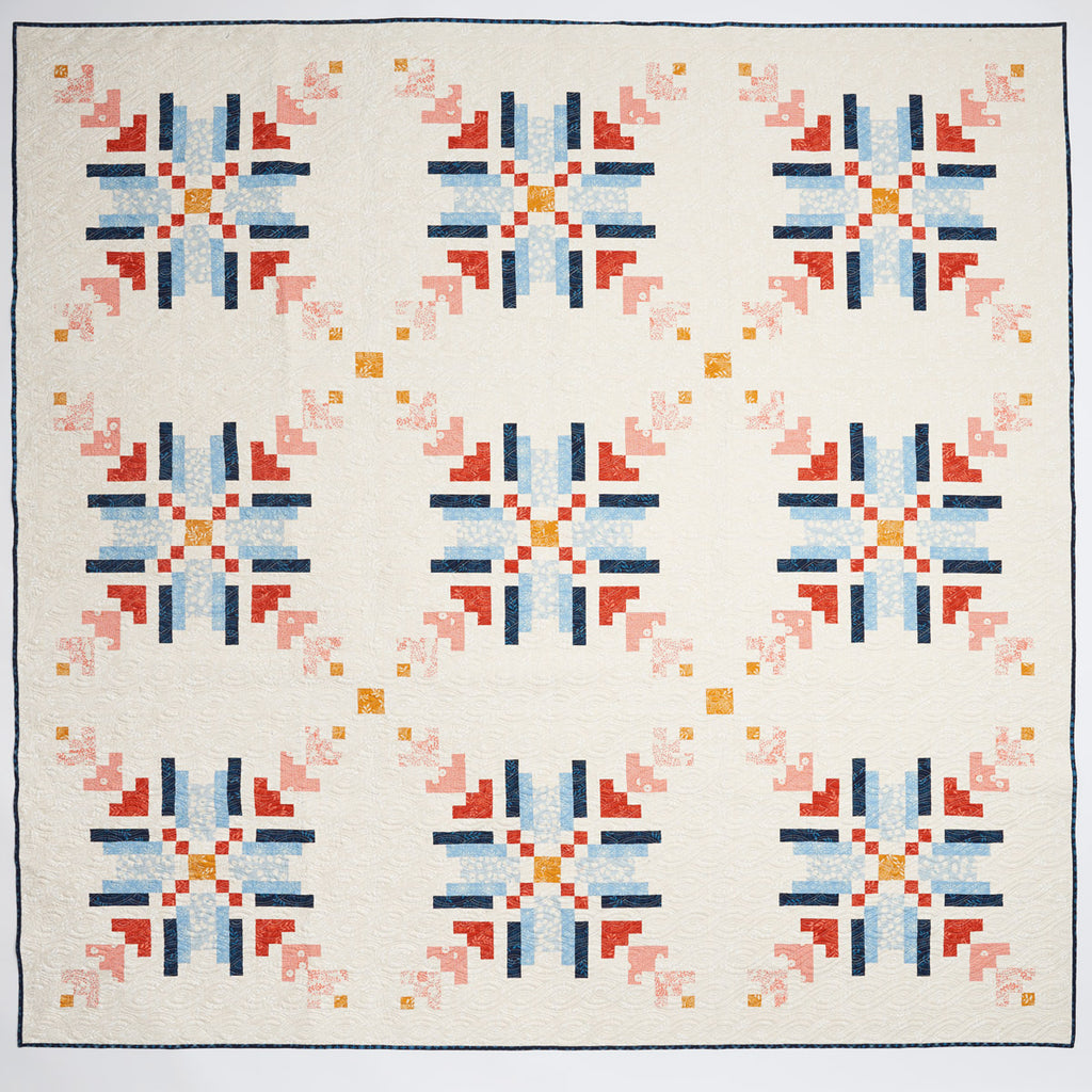 Quilt with geometric pattern featuring red, blue, and orange on a white background