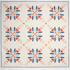 Quilt with geometric pattern featuring red, blue, and orange on a white background