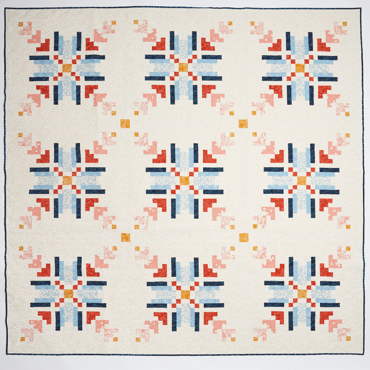 Quilt with geometric pattern featuring red, blue, and orange on a white background
