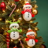 Decorative knitted snowman ornaments with scarves on a Christmas tree with lights and candy canes.