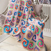 Colorful crocheted blanket draped over a chair with a neutral background