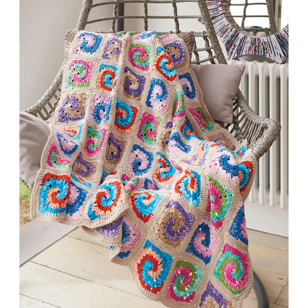 Colorful crocheted blanket draped over a chair with a neutral background