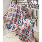Colorful crocheted blanket draped over a chair with a neutral background