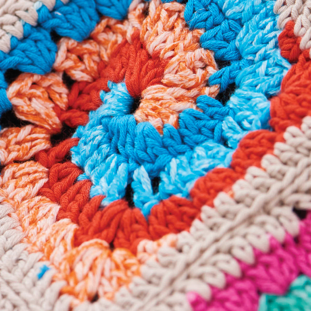 Close-up of a colorful crocheted fabric with blue, orange, and beige patterns.