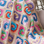 Colorful crocheted blanket with square patterns on a neutral background