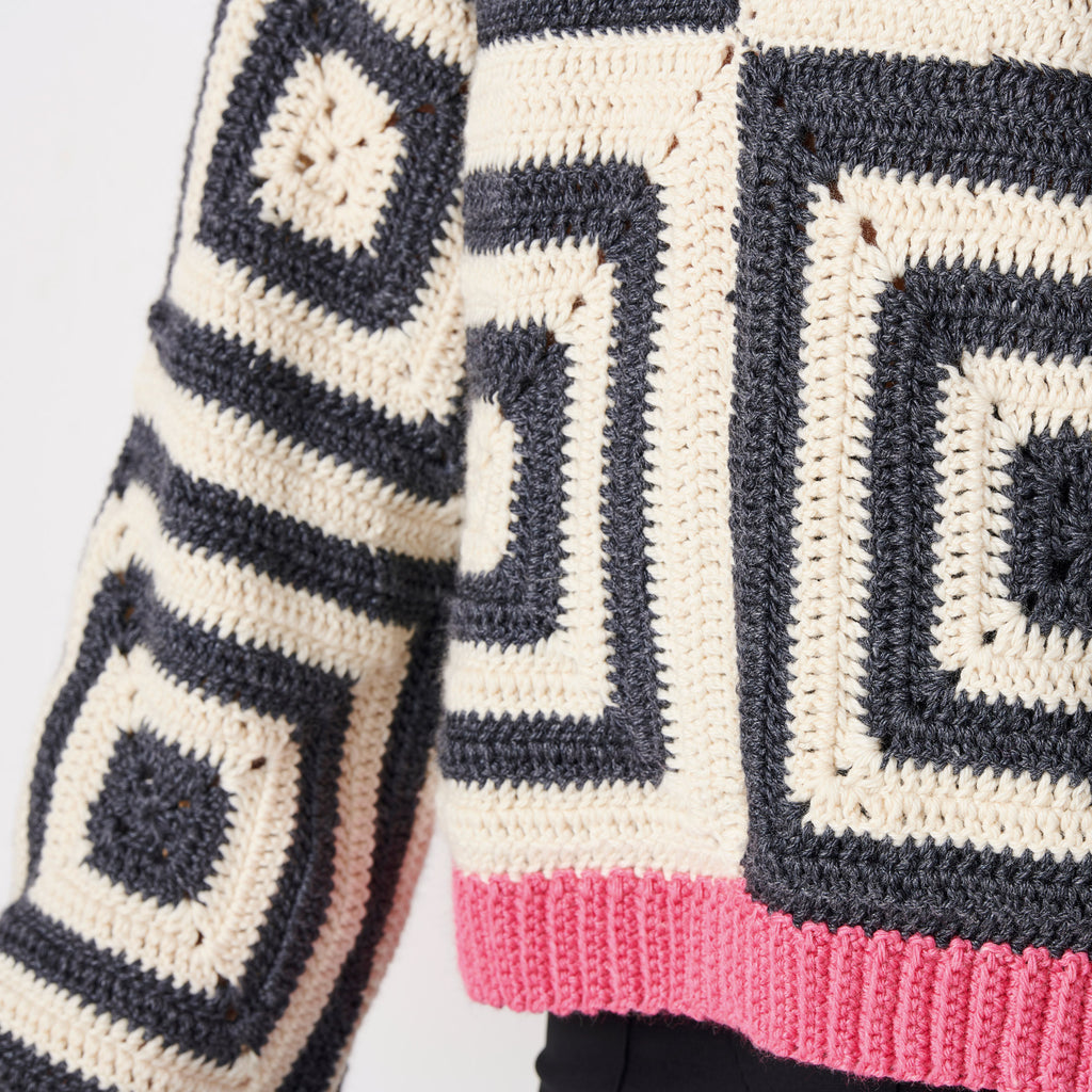 Close-up of a crocheted blanket with geometric pattern on a light gray background