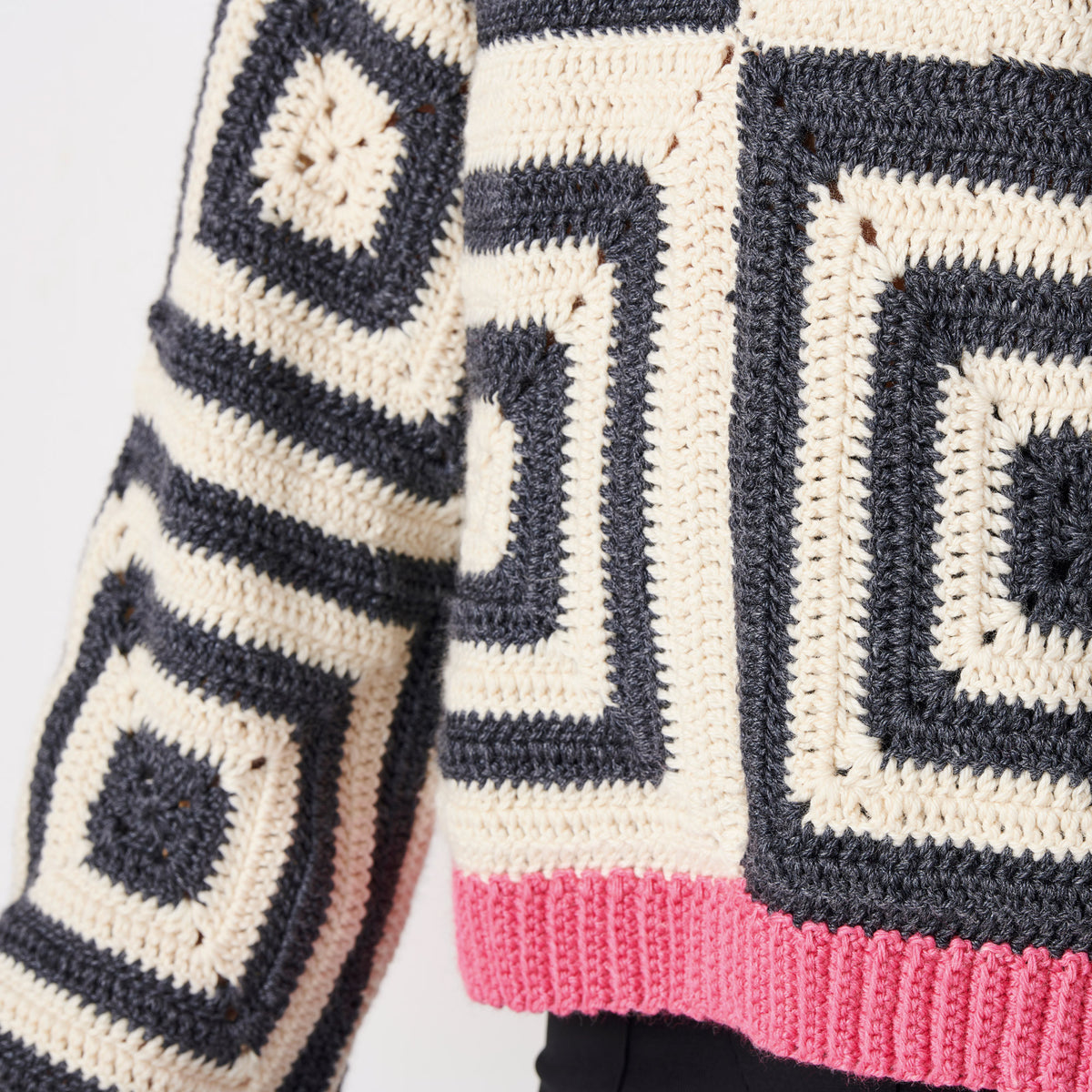 Close-up of a crocheted blanket with geometric pattern on a light gray background