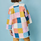 Person wearing a colorful quilted jacket against a light blue background
