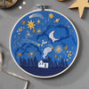Embroidery hoop with starry night design on a gray background
