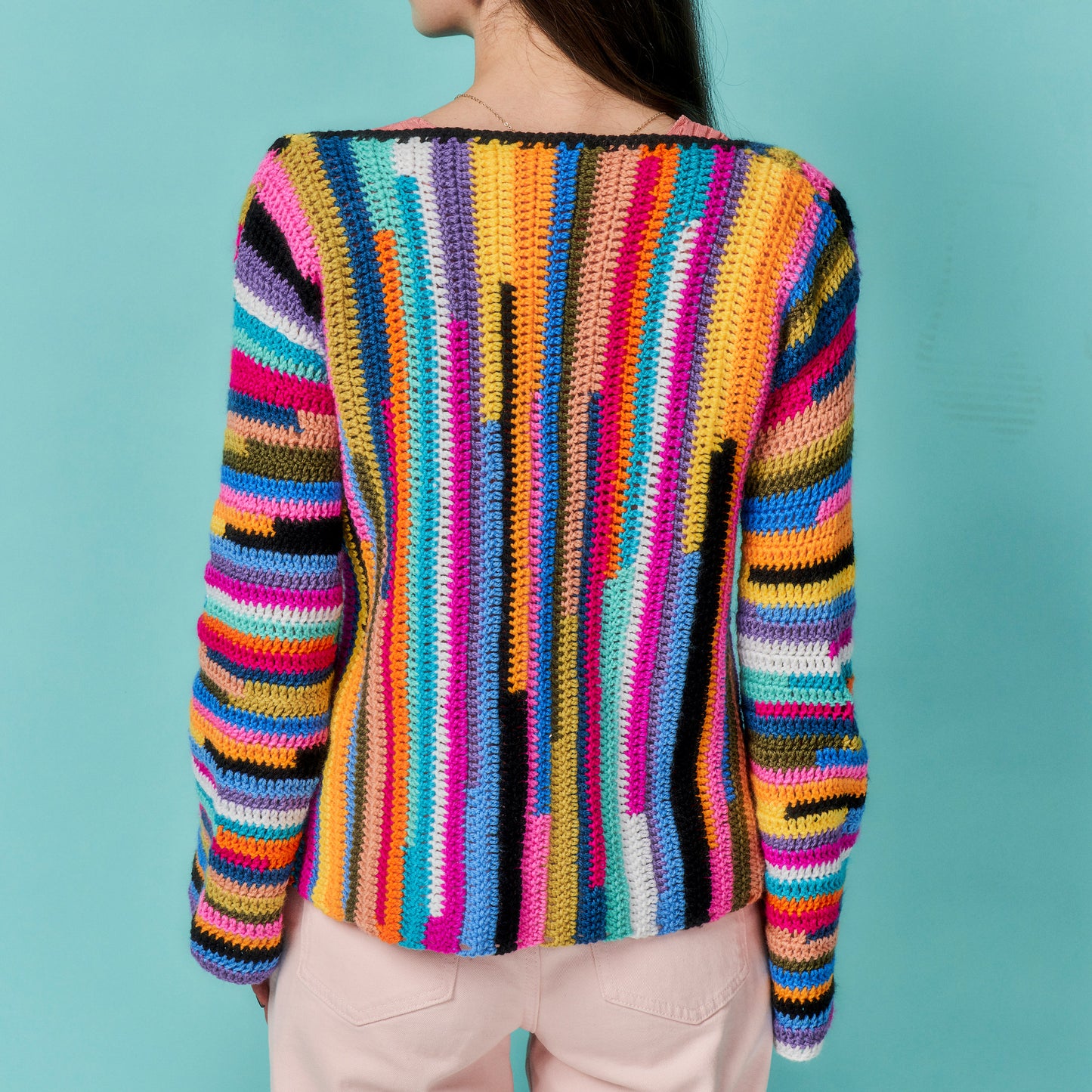 Colorful striped sweater worn by a person on a teal background