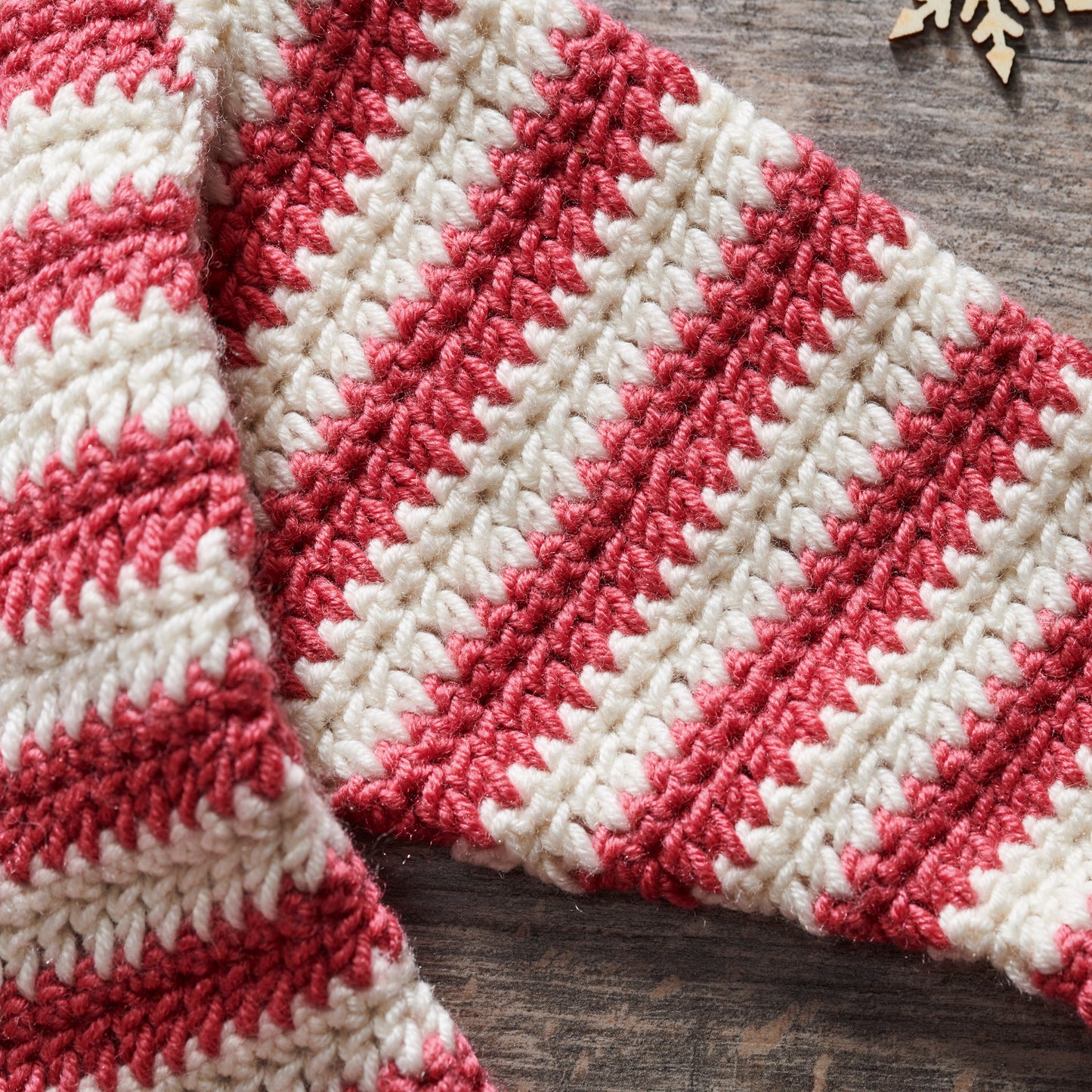 Red and white crocheted blanket on a wooden surface