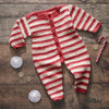 Red and white striped baby onesie on a wooden surface with Christmas decorations.