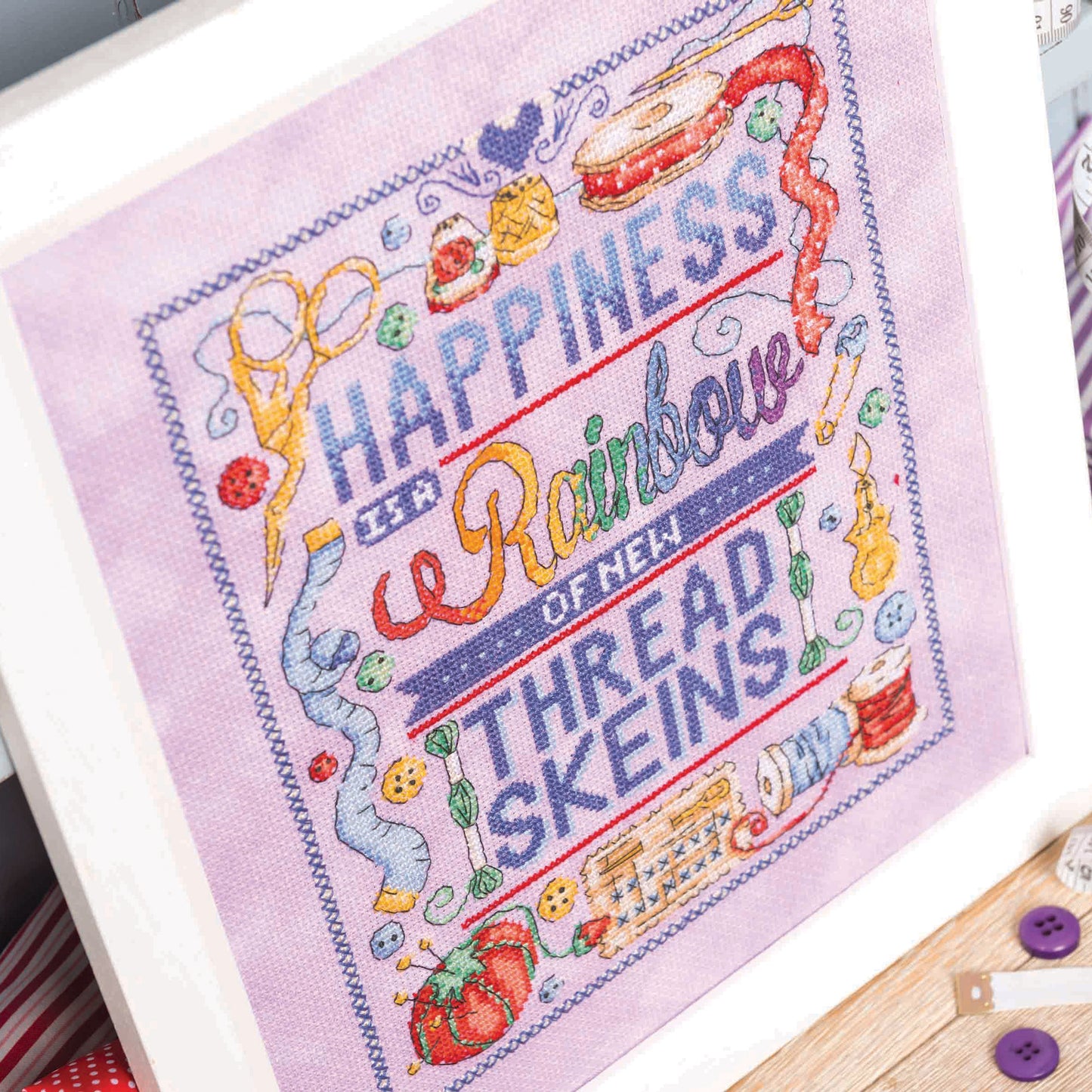 Embroidered fabric with colorful text and sewing-themed designs on a white background