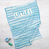 Blue and white striped baby blanket with 'LITTLE 1' text on a light wooden surface.