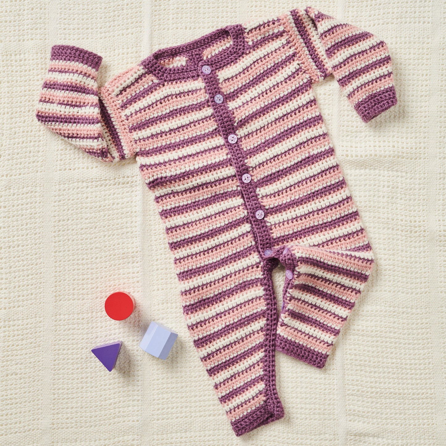 Striped baby romper with buttons on a textured surface