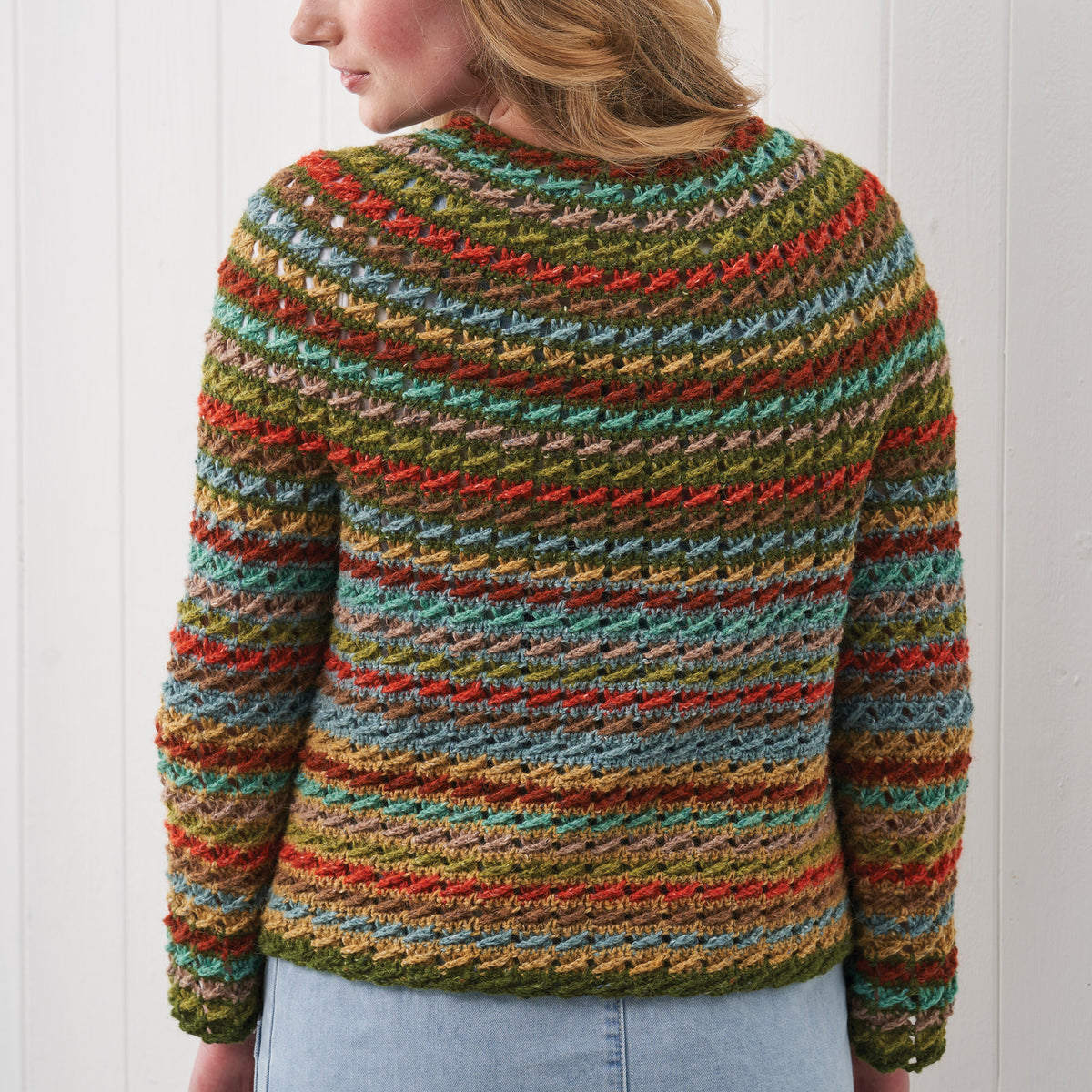 Multicolored striped sweater worn by a person against a white background
