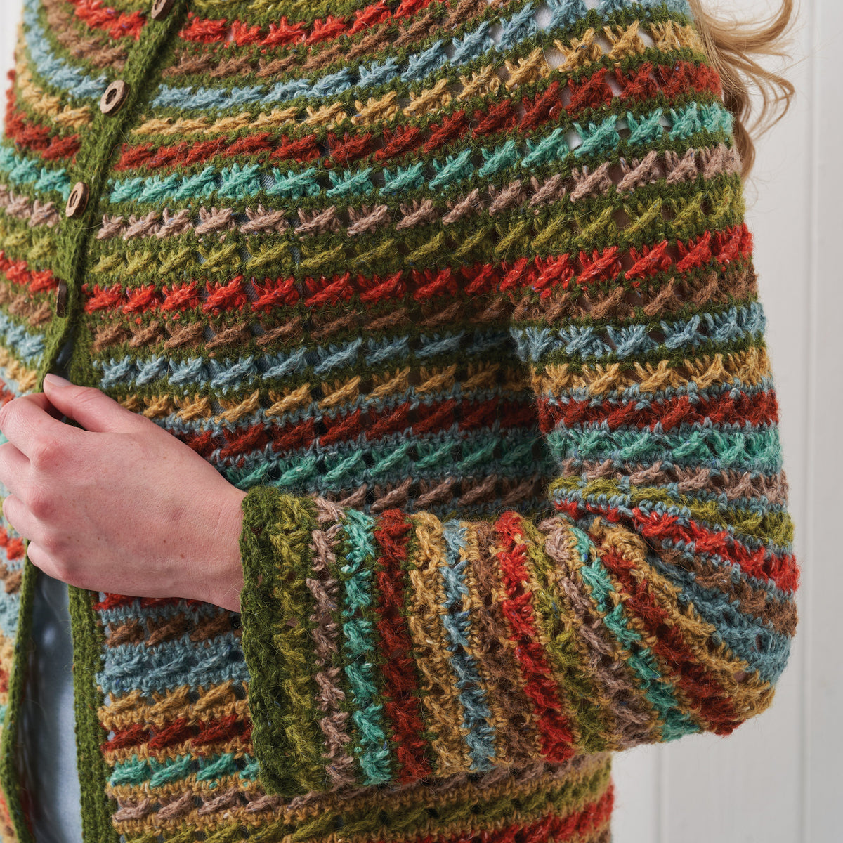 Multicolored crochet cardigan with a person wearing it, holding their arm.