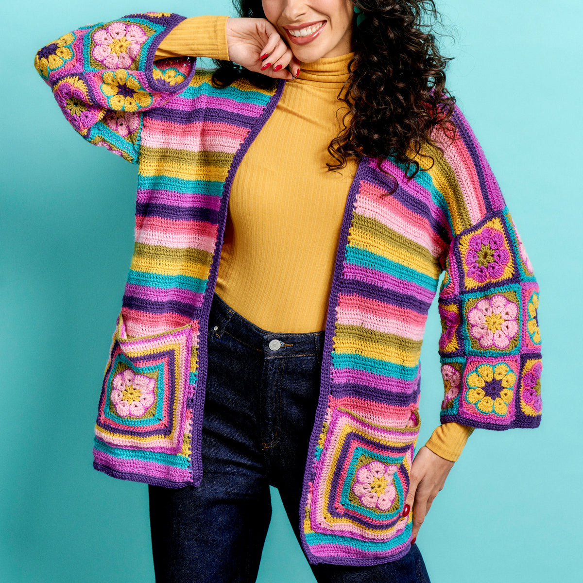 Woman wearing a colorful crochet cardigan against a blue background