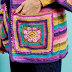 Colorful crocheted bag with a square pattern against a blue background