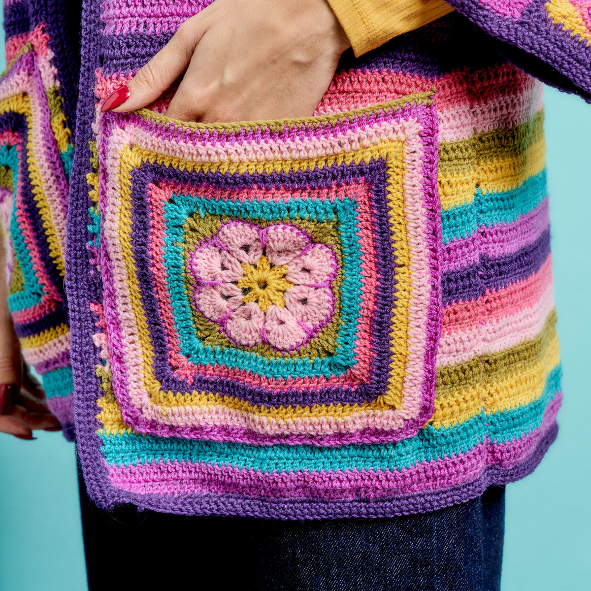 Colorful crocheted bag with a square pattern against a blue background