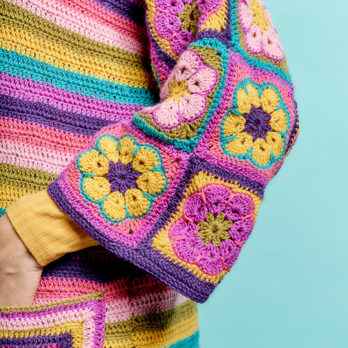Colorful crocheted blanket with floral patterns on a light blue background