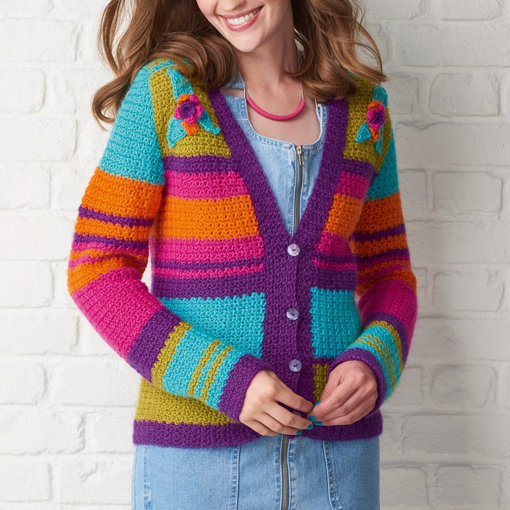 Person wearing a colorful striped cardigan against a white brick wall.