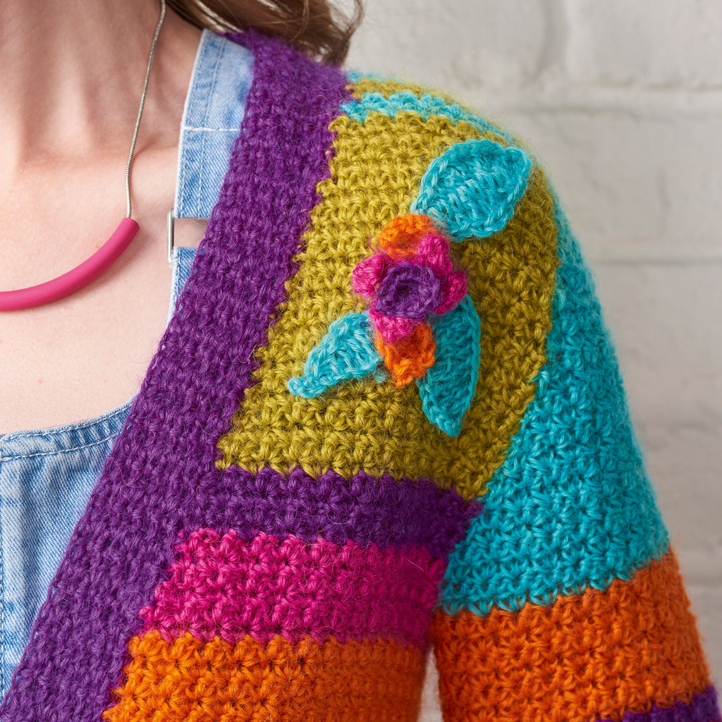Colorful crocheted cardigan with a floral design on a neutral background