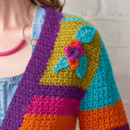 Colorful crocheted cardigan with a floral design on a neutral background
