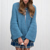 Person wearing a blue crochet cardigan against a white background