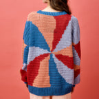 Person wearing a colorful geometric-patterned sweater against a pink background