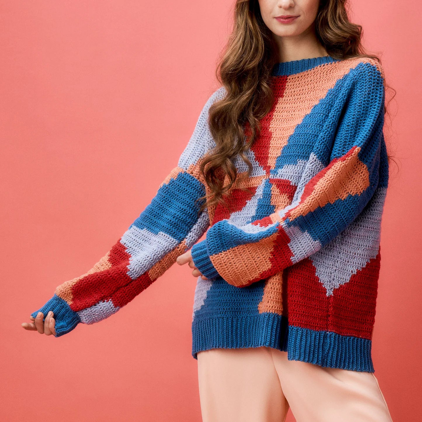 Woman wearing a colorful, patterned sweater against a pink background