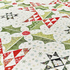 Quilt made from Christmas-themed fabrics featuring snowmen, holly leaves, and snowflakes.