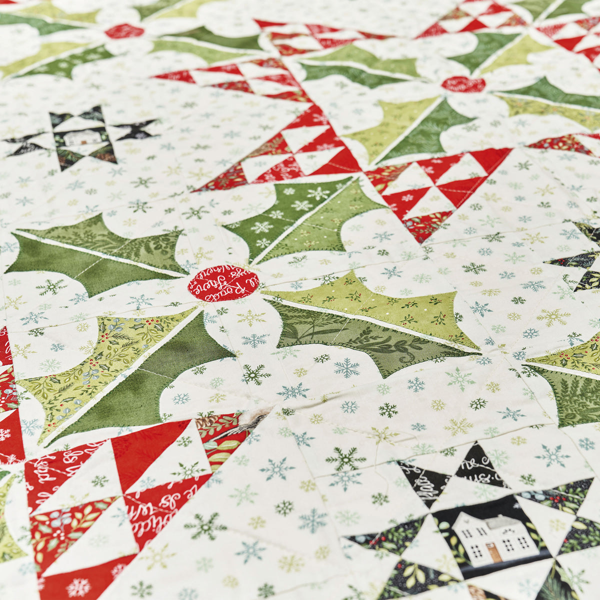 Quilt made from Christmas-themed fabrics featuring snowmen, holly leaves, and snowflakes.