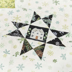 Quilt block with house design and snowflakes on a white background