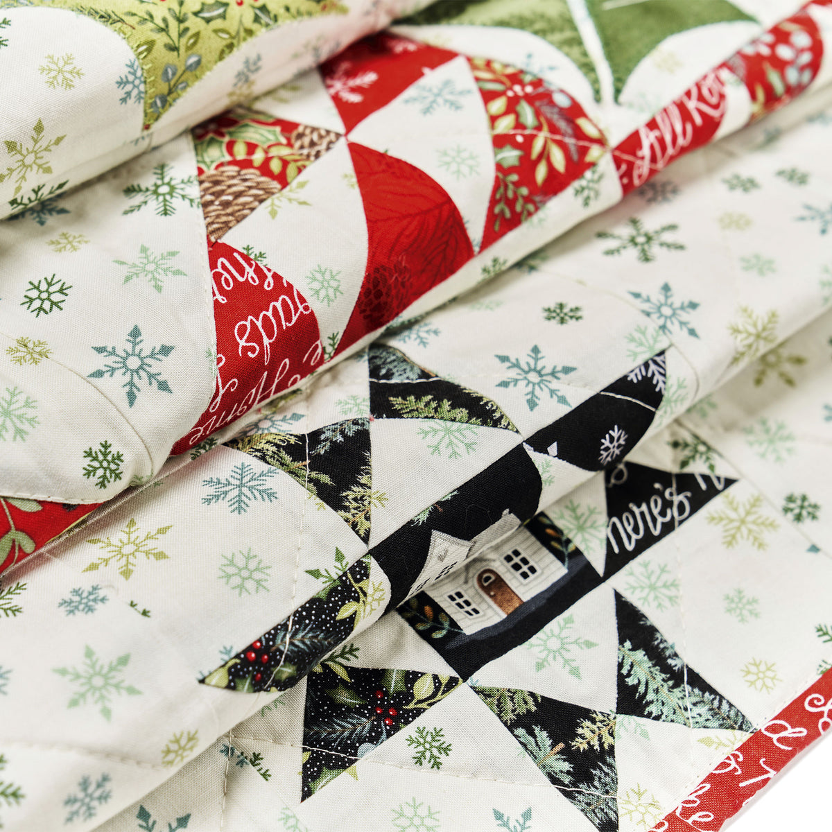Quilt with Christmas-themed fabric featuring snowflakes, trees, and house designs.