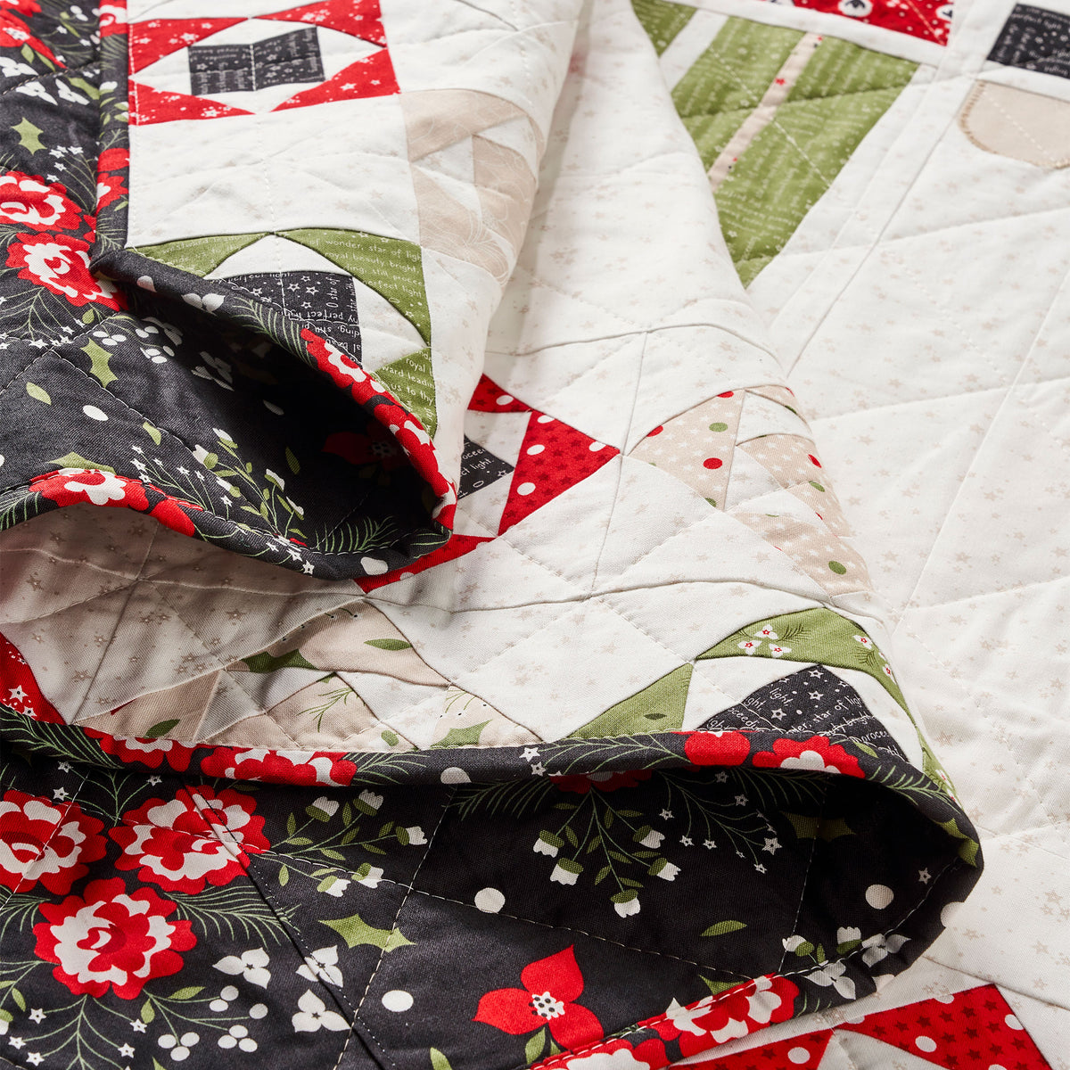 Close-up of a quilt with floral and geometric patterns in red, green, and white.