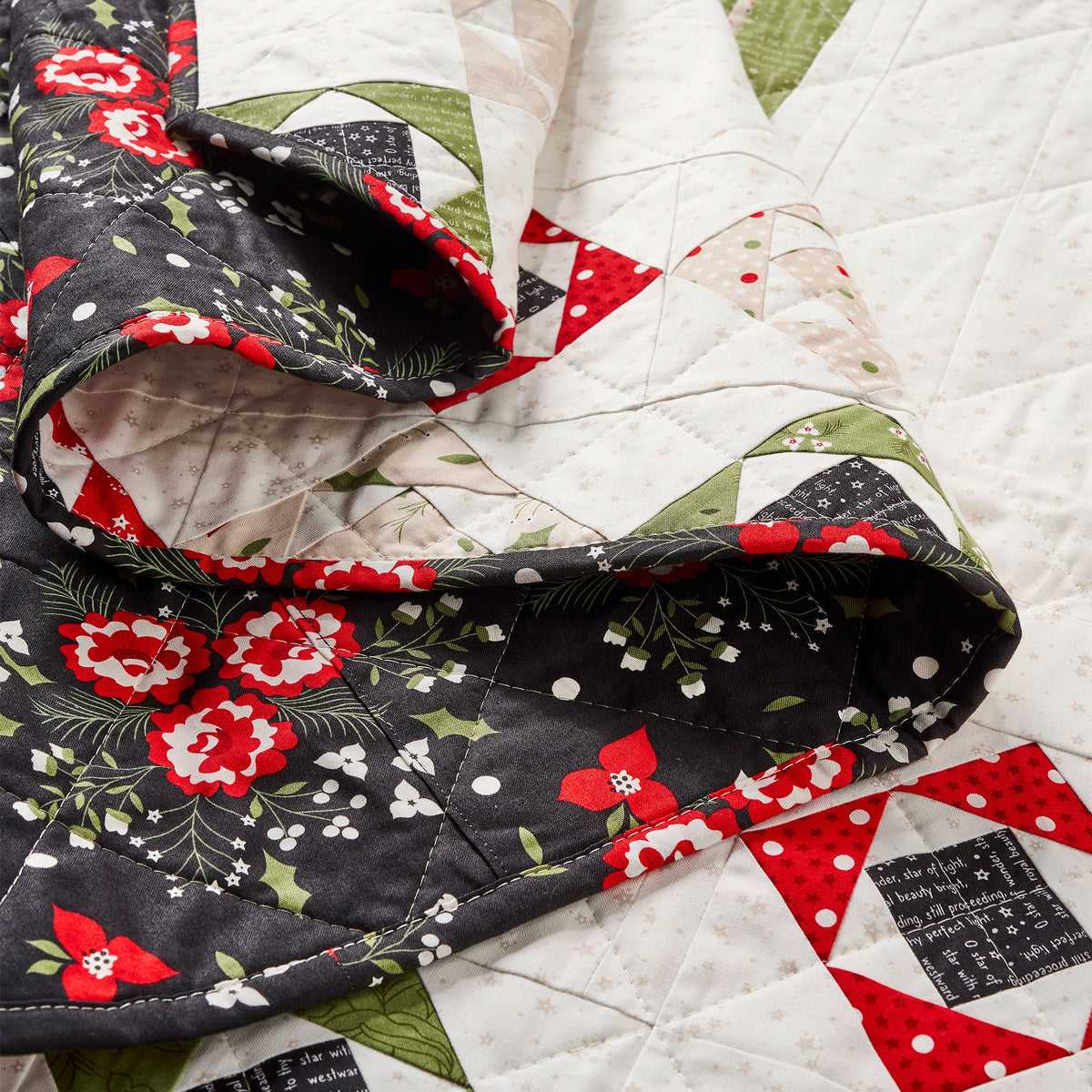 Quilt with floral and geometric patterns in red, black, and white on a white background