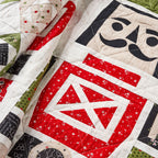 Quilt with geometric patterns featuring red, black, and white colors.