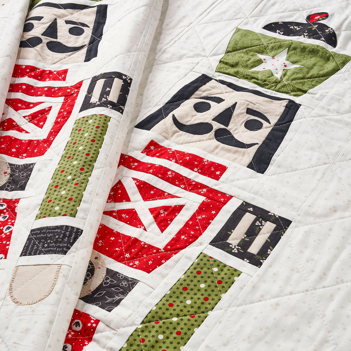 Quilt with robot-themed blocks in red, green, and black on a white background