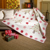 Decorative quilt with star patterns draped over a sofa in a cozy living room with Christmas decorations.