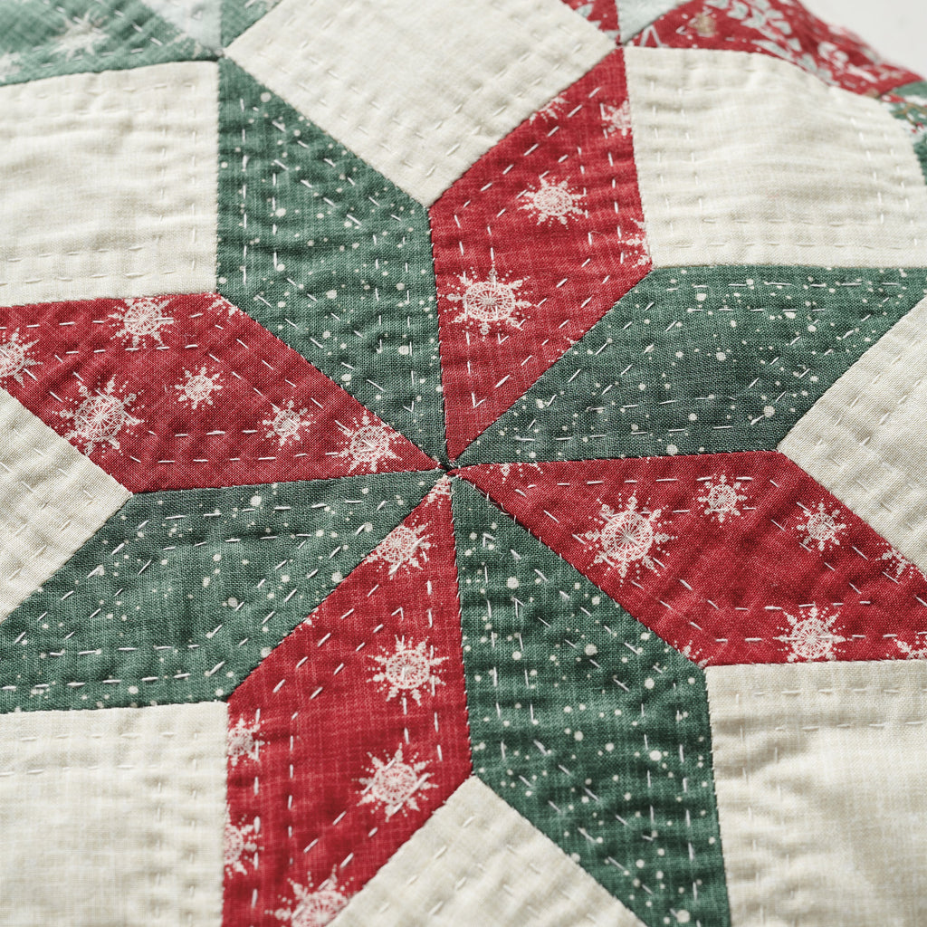 Close-up of a quilt with red, green, and white hexagonal patterns.