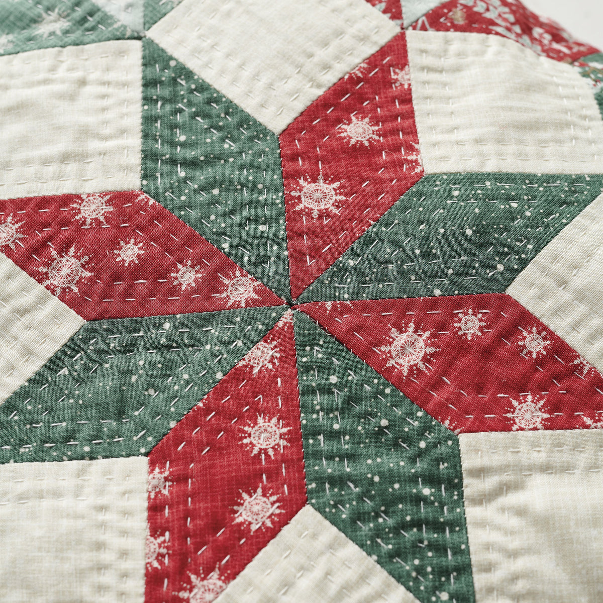 Close-up of a quilt with red, green, and white hexagonal patterns.