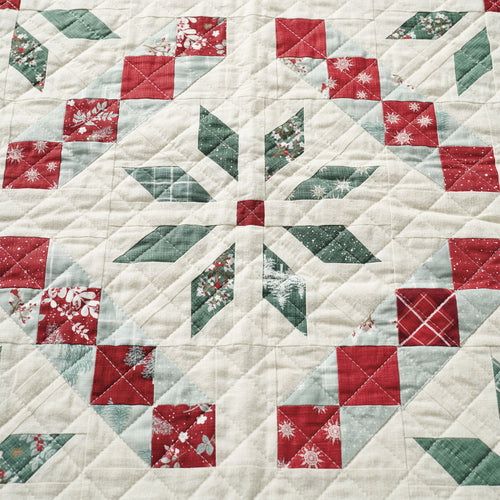 Quilt with a geometric pattern featuring red, green, and white squares.