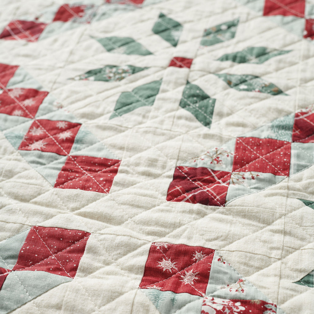 Close-up of a quilt with red, green, and white diamond patterns