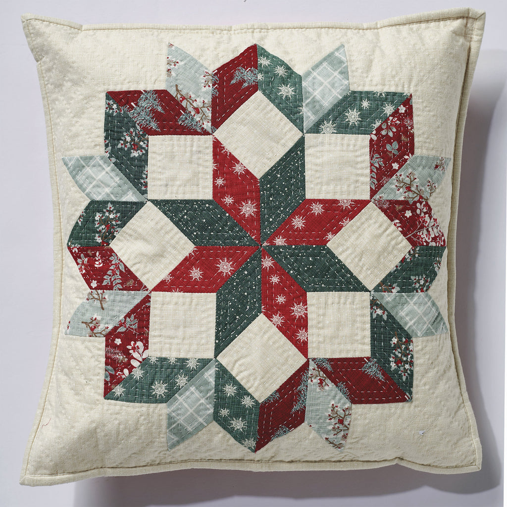 Quilted pillow with a geometric pattern in red, green, and white on a light background