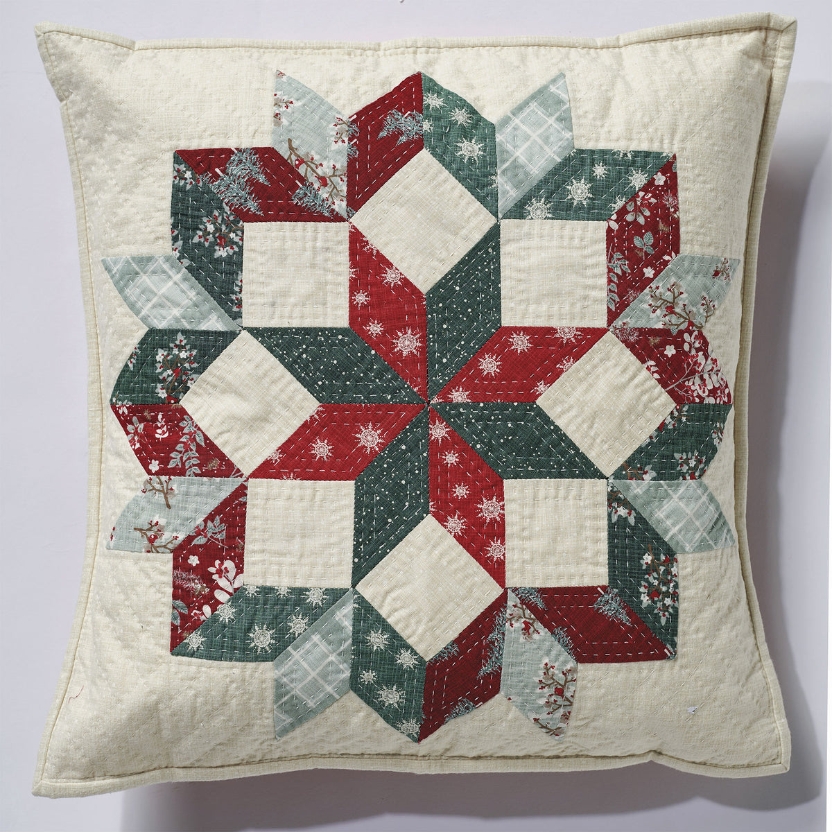 Quilted pillow with a geometric pattern in red, green, and white on a light background