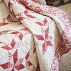 Red and white quilt with star pattern on a bed