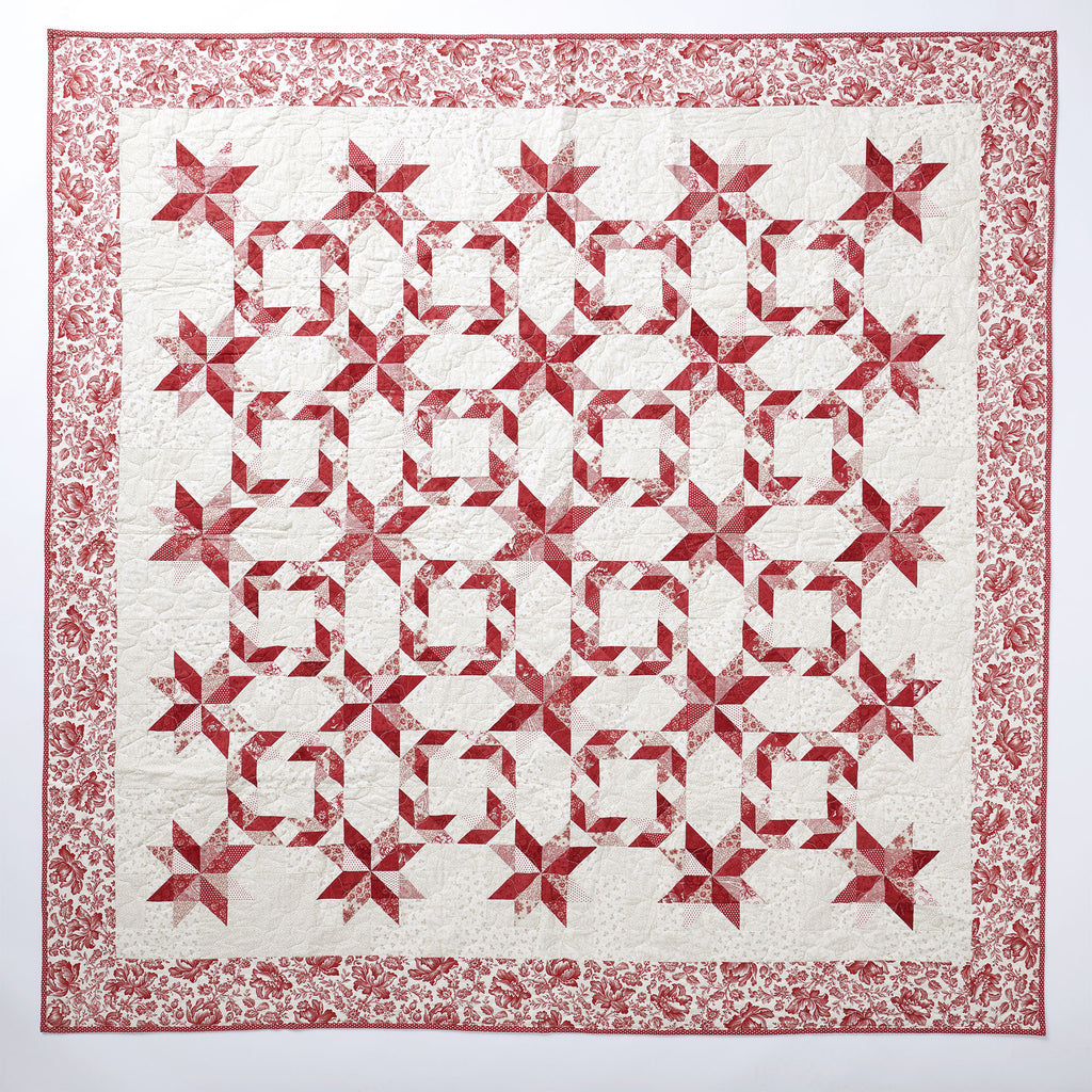 Quilt with red and white star pattern on a white background