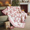 Red and white quilt draped over a sofa in a cozy living room with a Christmas tree and presents.