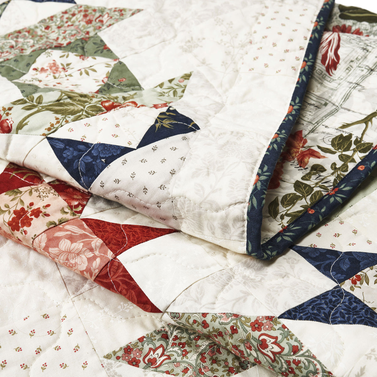 Quilt with floral and geometric patterns in red, white, and blue.